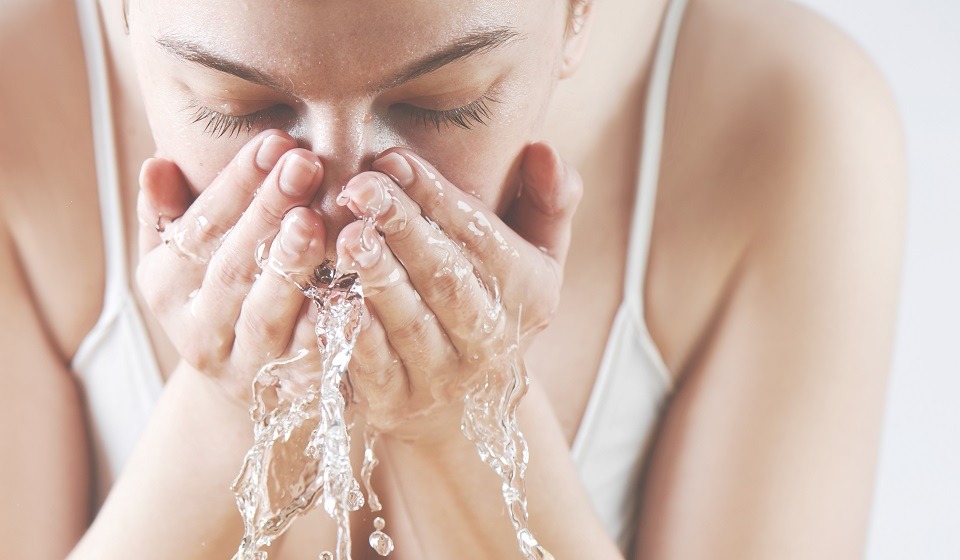 Nainen pesee kasvojaan vedellä